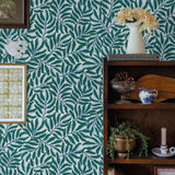 Room interior with green leaf-patterned wallpaper, bookshelf, and decorative items.