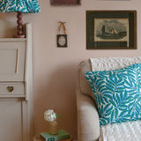 Living room with a beige sofa, green and white lampshade, and framed pictures on the wall.