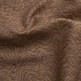 Detail of gently draped printed fabric with watercolor swirling stripe pattern in tonal warm terracotta brown.