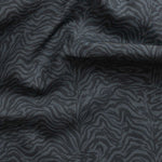 Detail of gently draped printed fabric with watercolor swirling stripe pattern in tonal navy blue.