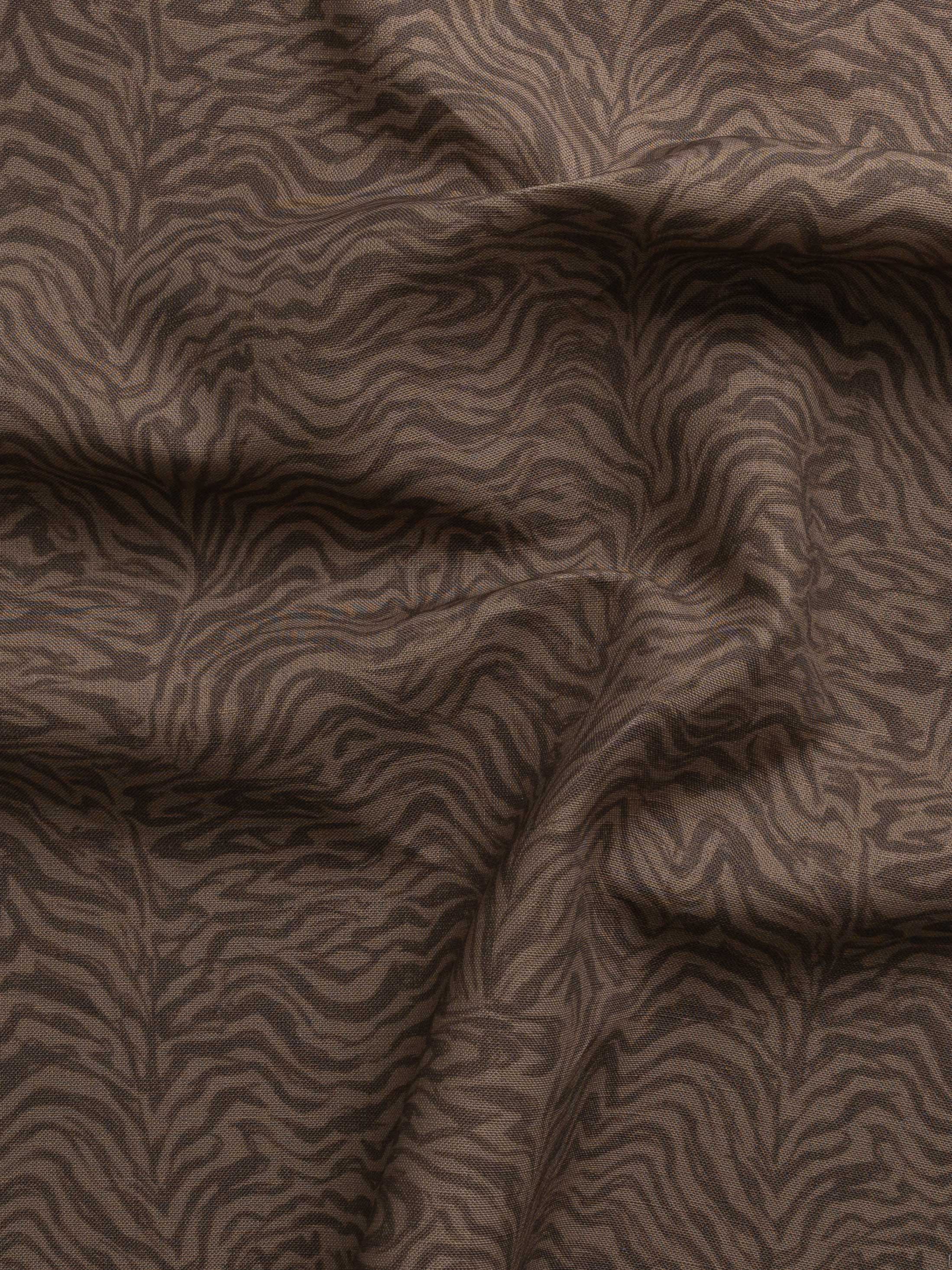 Detail of gently draped printed fabric with watercolor swirling stripe pattern in tonal warm brown.