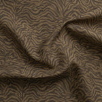 Detail of gently draped printed fabric with watercolor swirling stripe pattern in tonal brown.