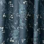 Draped printed fabric in a floral and dot pattern in blue and white on a navy field.