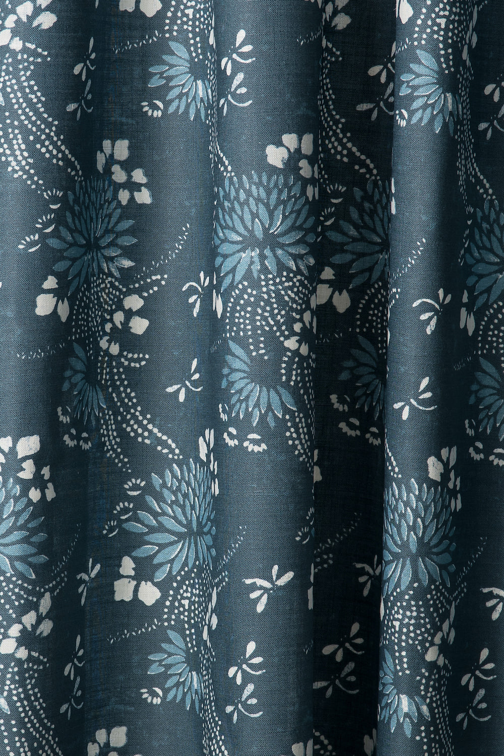 Draped printed fabric in a floral and dot pattern in blue and white on a navy field.