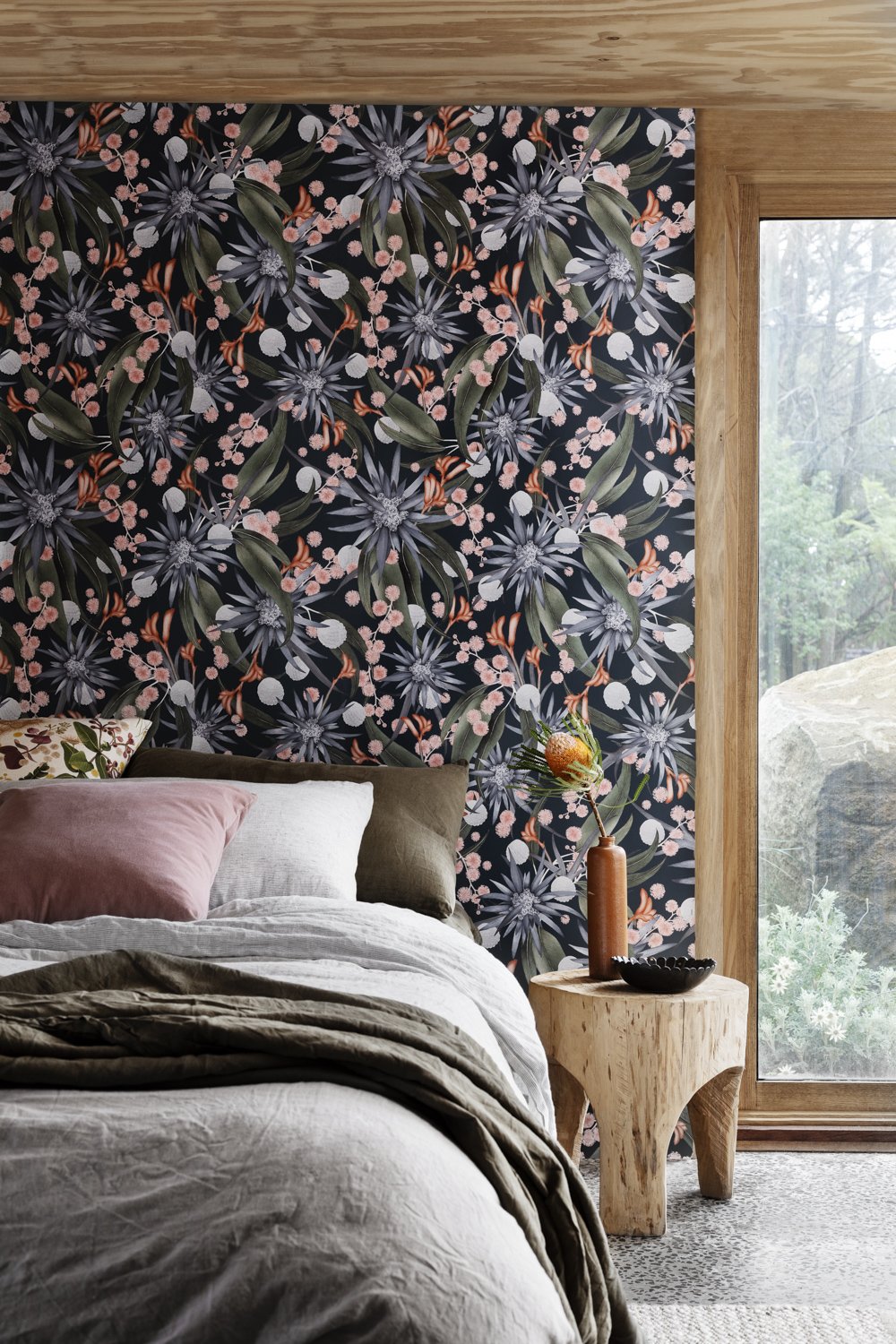 Bedroom with a large window and a wall papered in a large-scale botanical print in shades of blue, green, pink and navy.