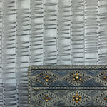 A metal end table stands in front of a wall papered in an undulating ribbon pattern in charcoal.