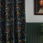 A wood-paneled wall and a curtain in a small-scale floral print on a black field.