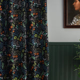 A wood-paneled wall and a curtain in a small-scale floral print on a black field.