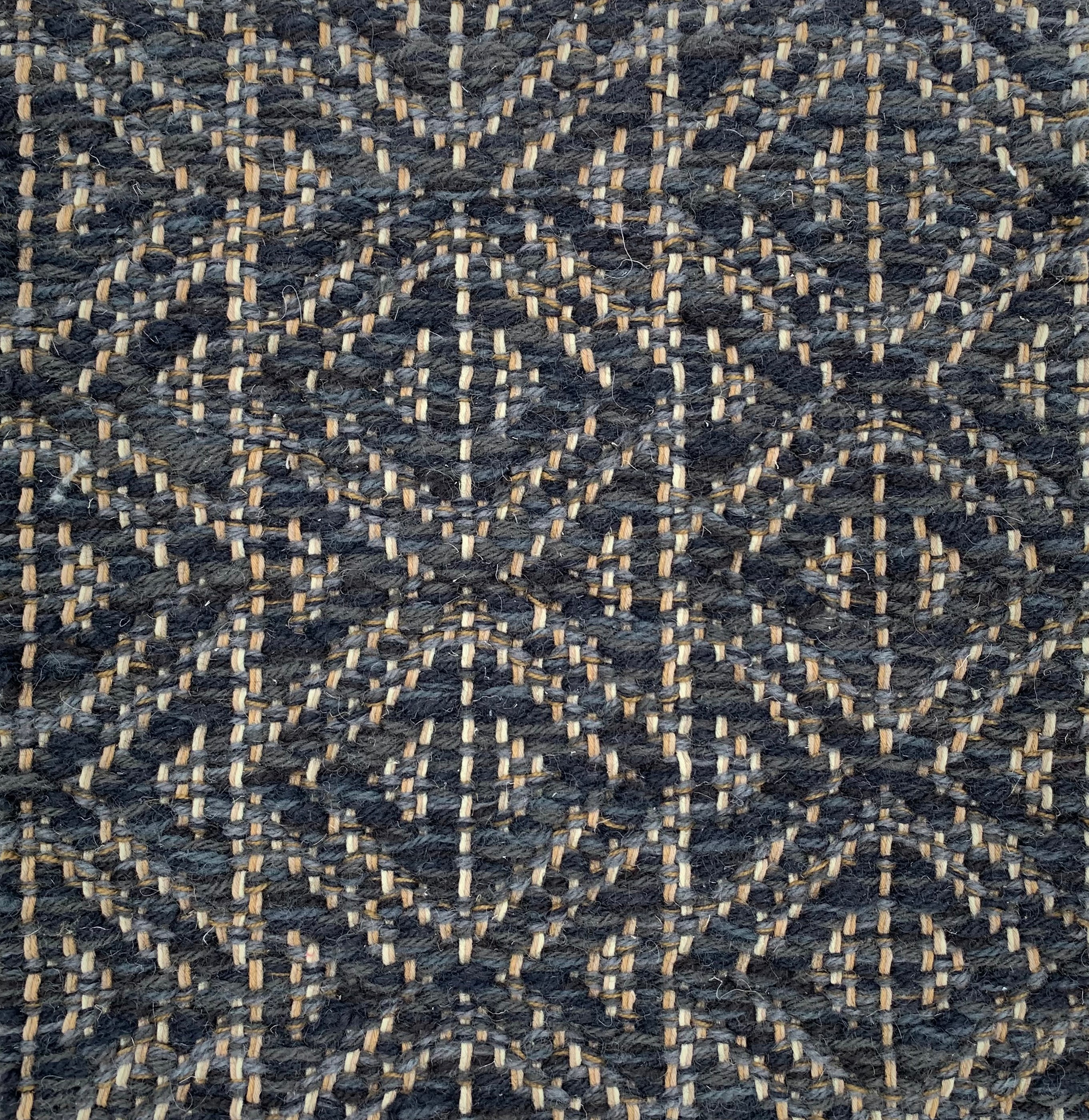 Handwoven rug detail in a diamond design in navy blue and black