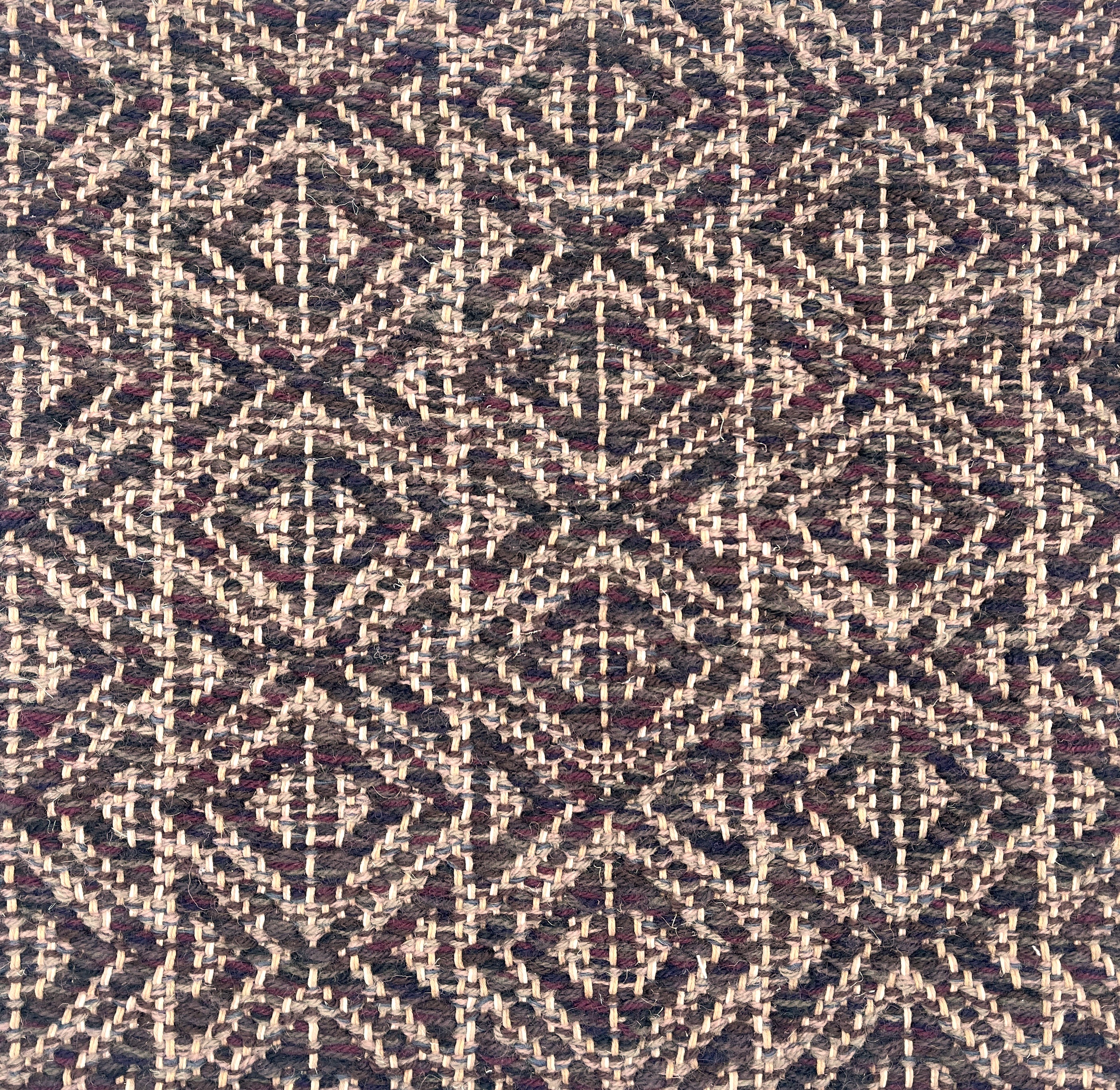 Handwoven rug detail in a diamond design in cream, purple and black