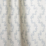 Draped fabric with stripe pattern of stylized  blue leaves on a beige background
