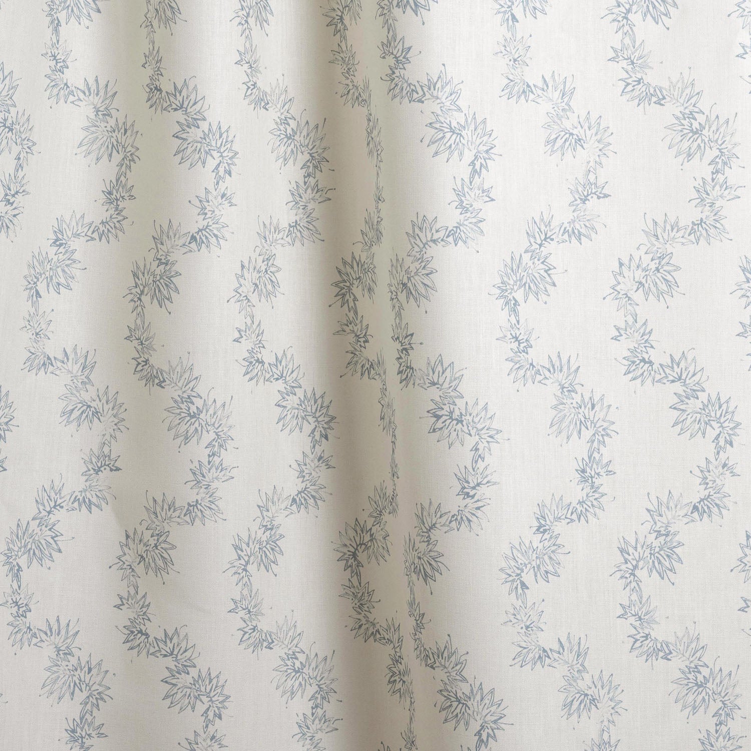 Draped fabric with stripe pattern of stylized  blue leaves on a beige background