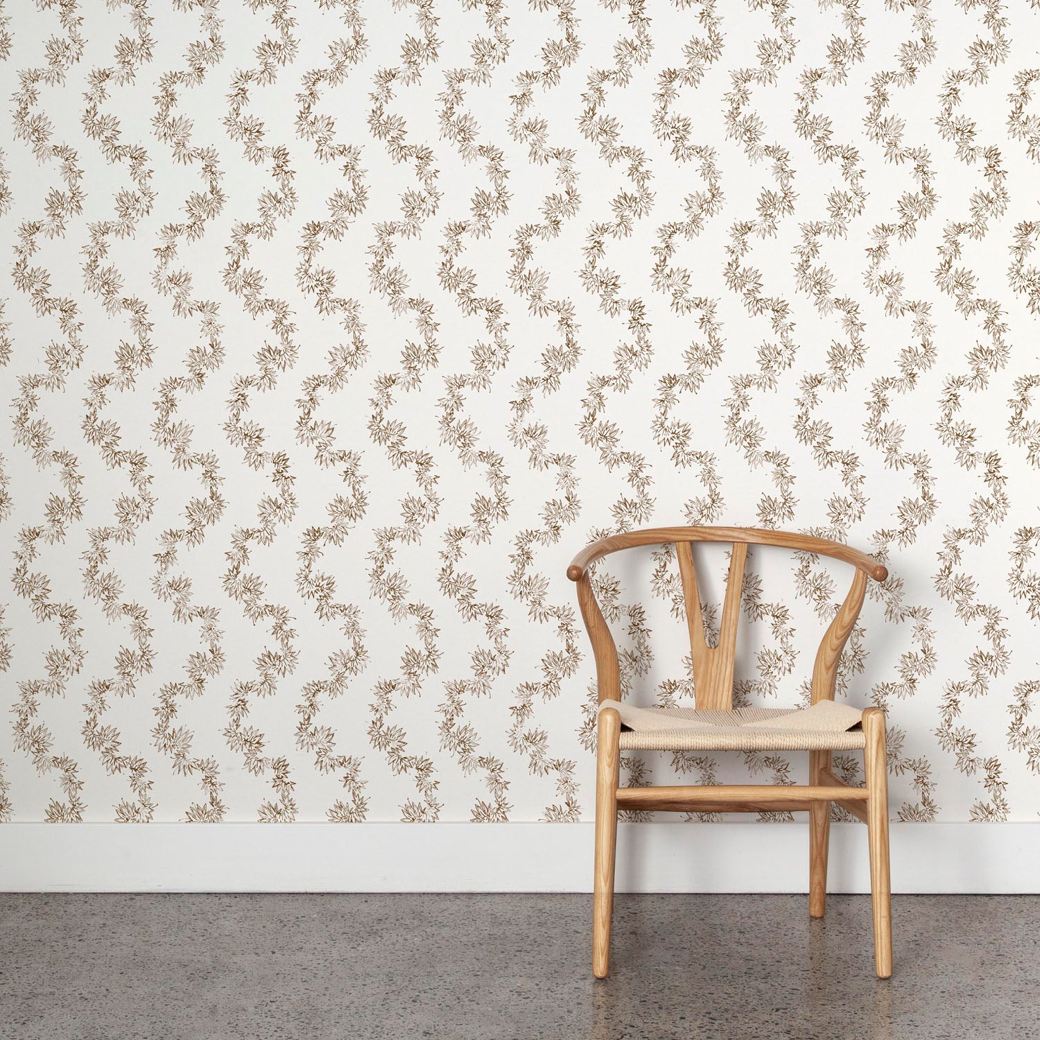 Wooden chair against wallpaper with stripe pattern of stylized dark brown leaves on a cream background