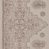 Detail of fabric in a dense paisley border print in brown on a tan field.