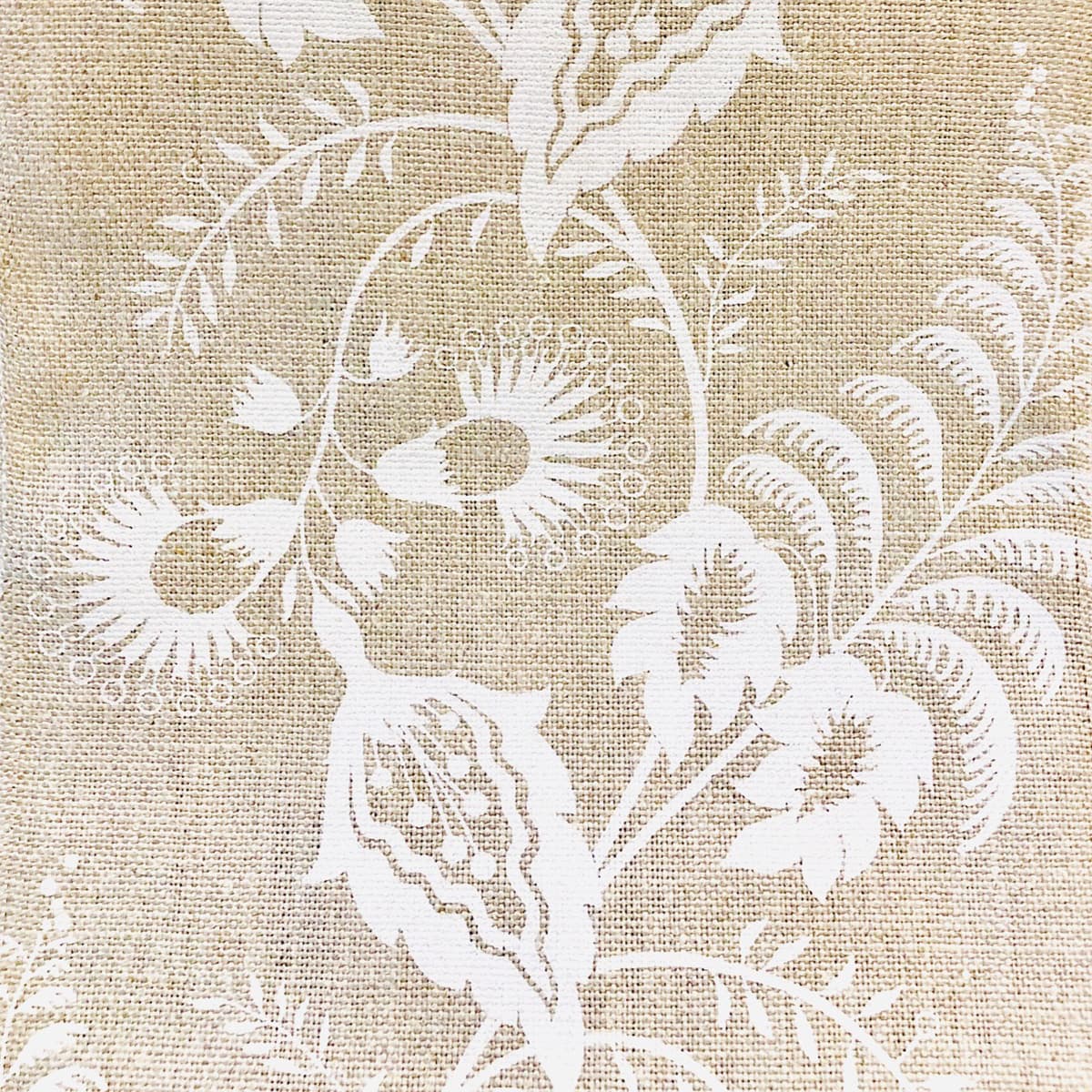 Detail of fabric in a floral trellis print in white on a tan field.
