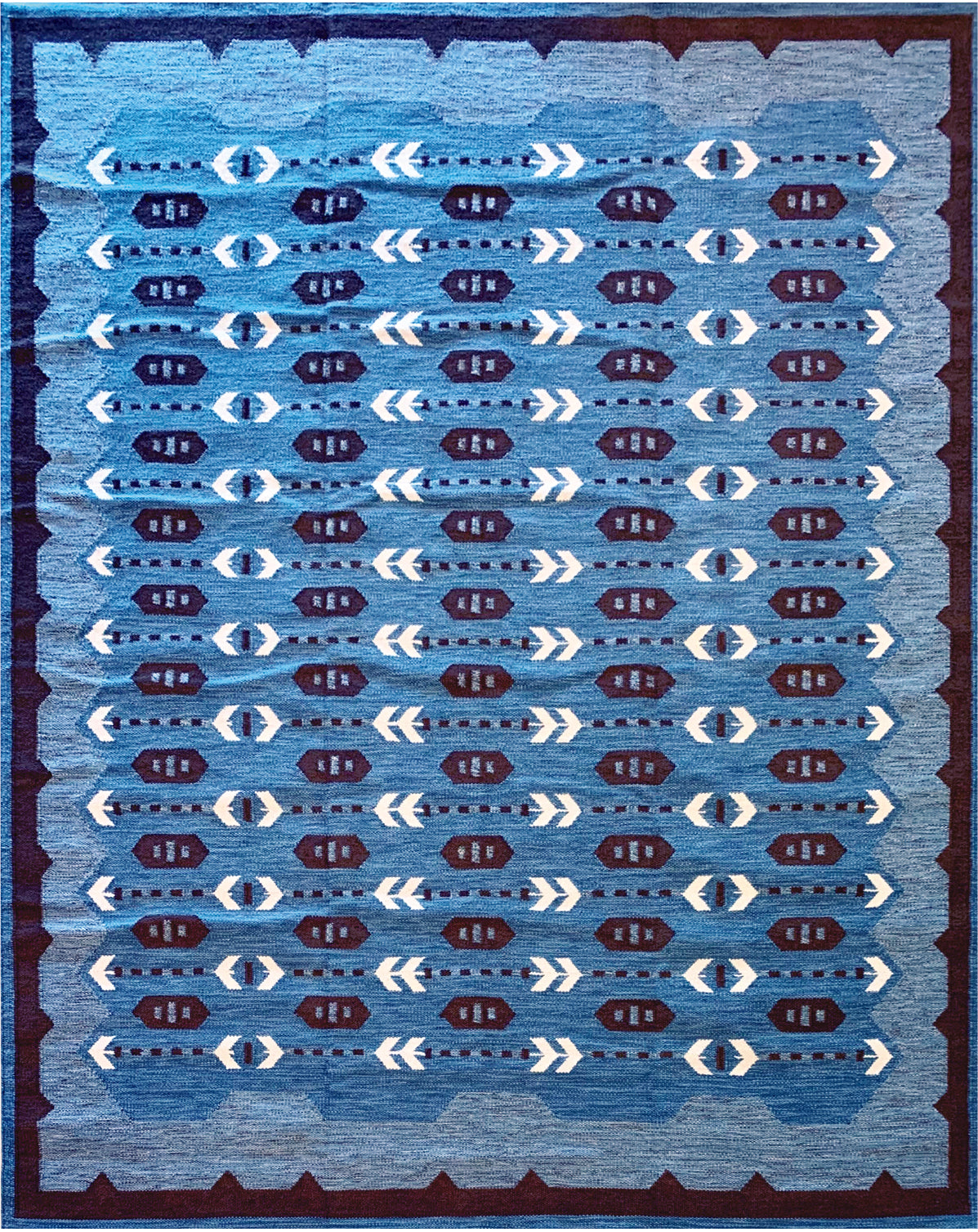 Handwoven rug in a Swedish arrow design in brown and white on a green field. 