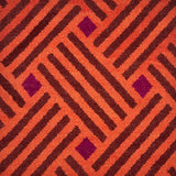 A woven rug with diagonal stipes in orange and brown and diamonds of purple.