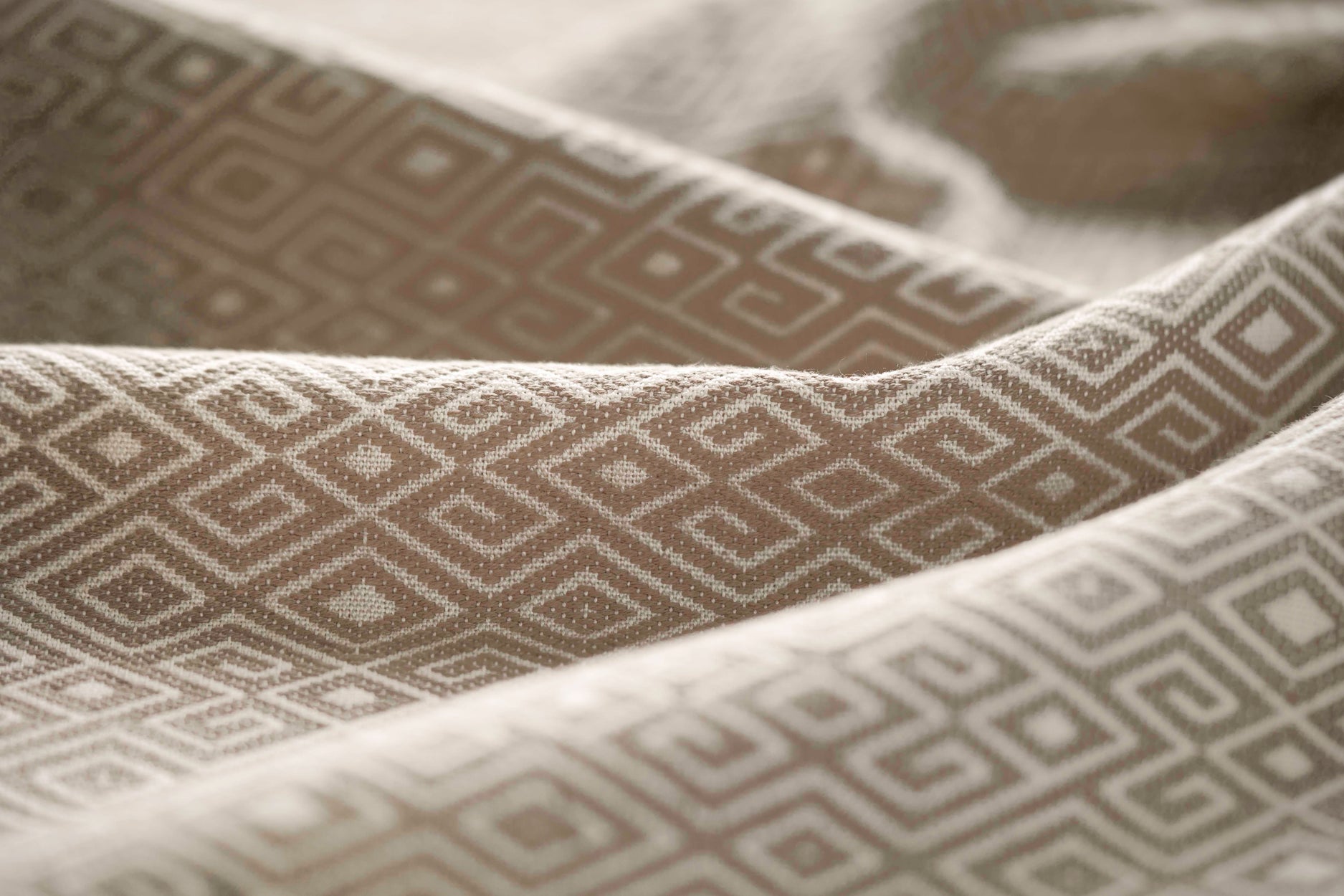 Close-up of textured fabric with geometric pattern in beige gently folded