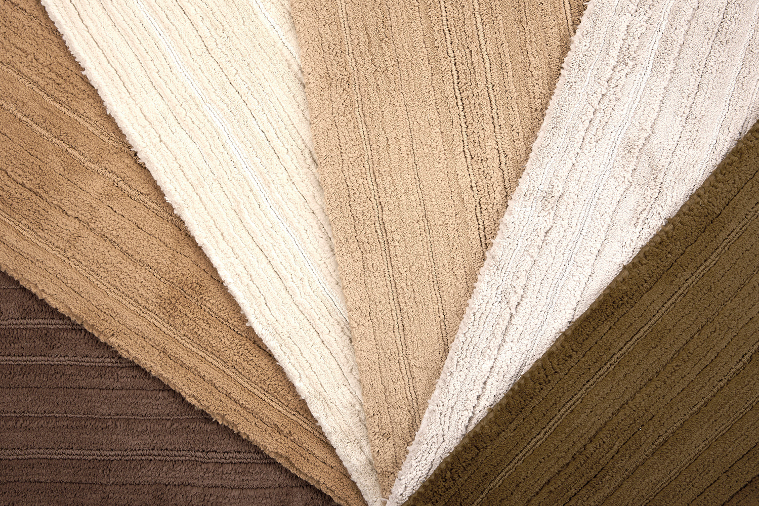 Array of froadloom carpet samples with ribbed and cut pile stripe in neutral colors from brown to ivory.