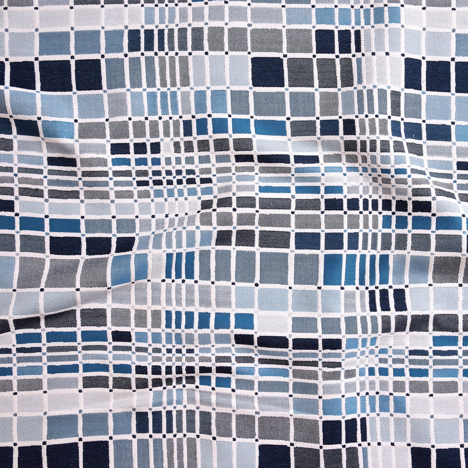 Close up of gently draped woven Indoor-Outdoor fabric with complex windowpane pattern in white with squares of grey, slate blue, marine and navy.