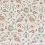 Detail of fabric in a floral paisley print in shades of rust and green on a cream field.