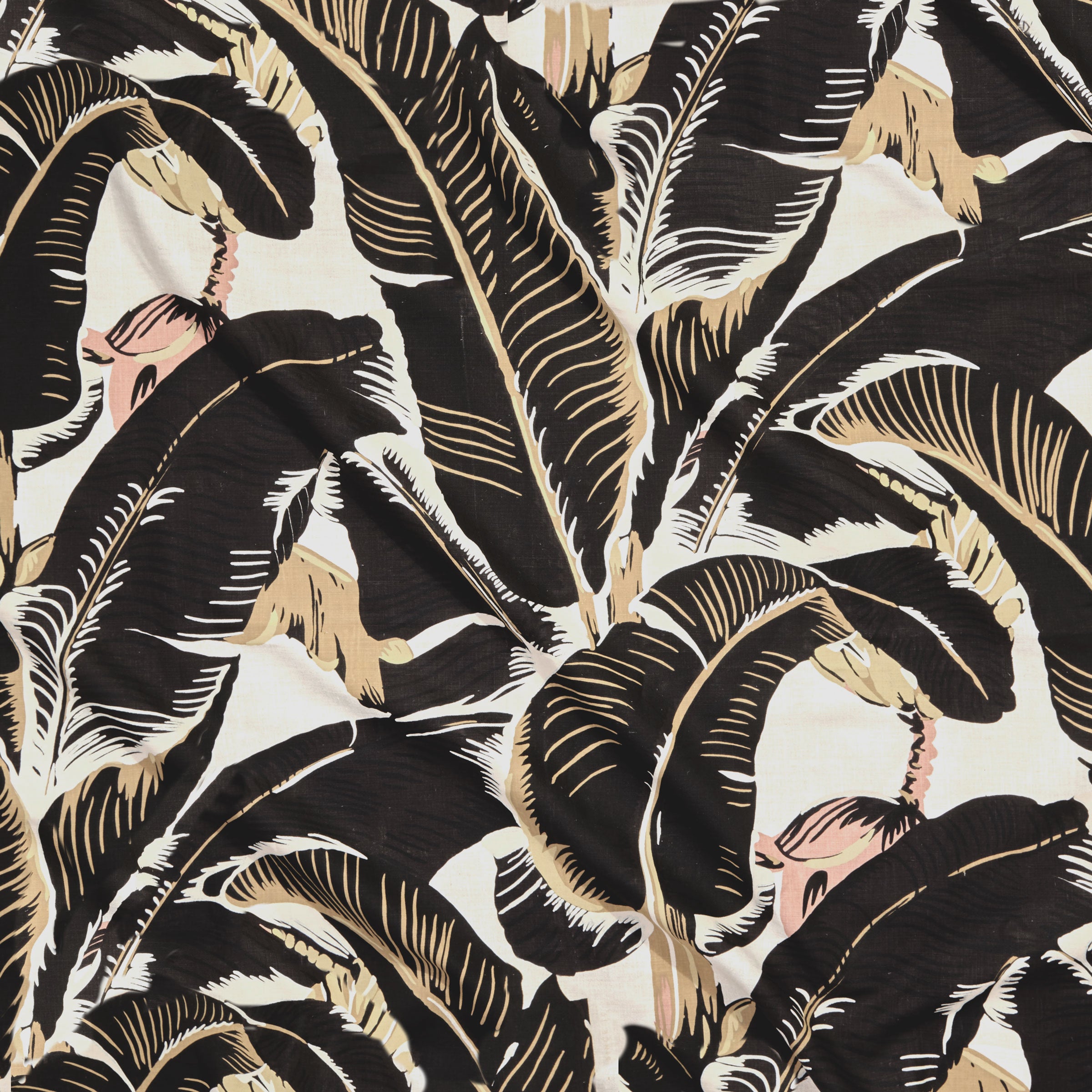 Close up of gently draped printed linen with bold banana leaf in shades of black, tan and light pink on white.