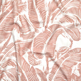 Close up of gently draped printed linen with bold high contrast tropical banana leaf pattern in pink on white. 