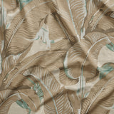 Close up of gently draped printed linen with bold banana leaf in shades of taupe and aqua blue on white.
