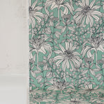 Draped fabric yardage in a floral print in black and white on a light turquoise field.