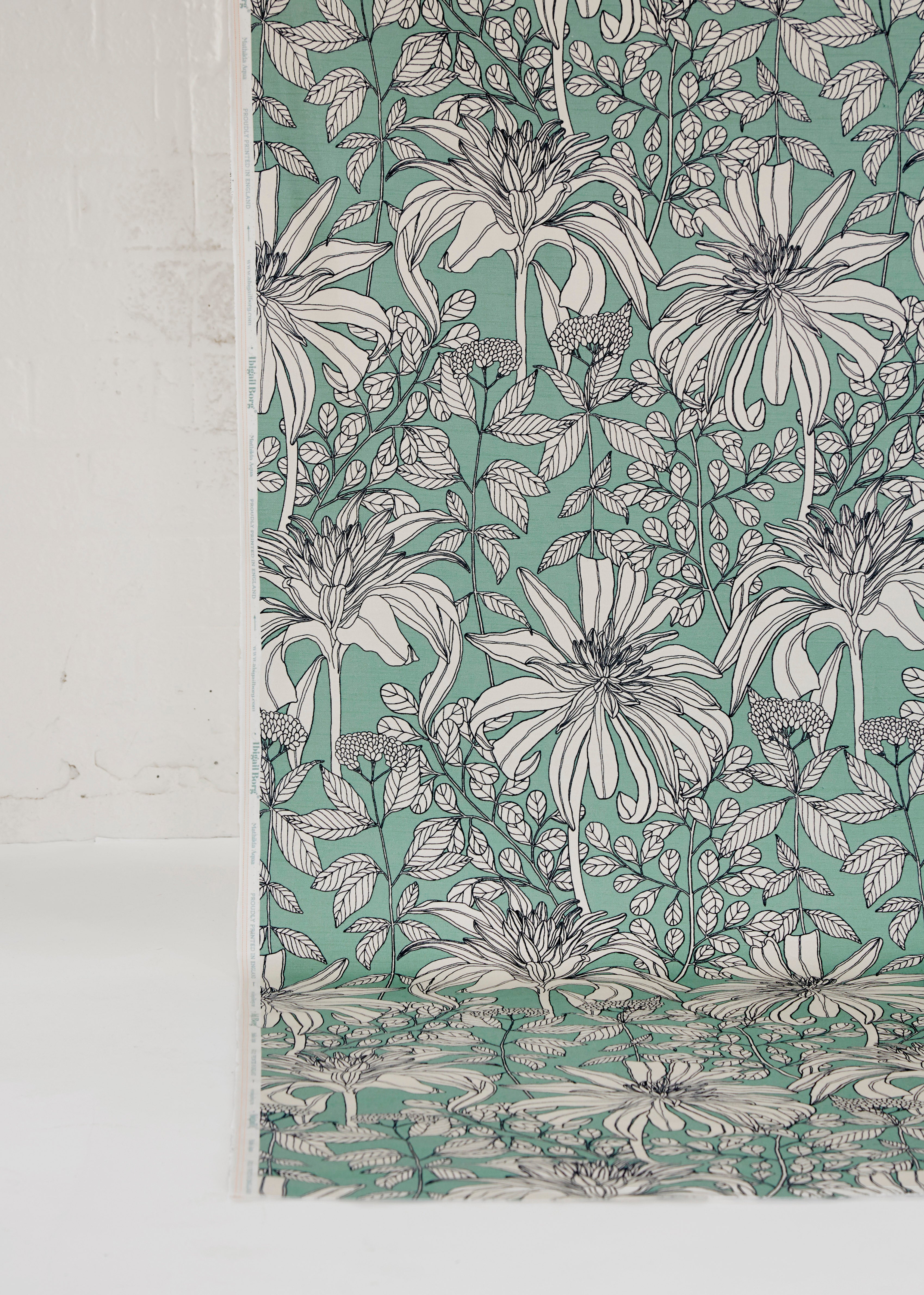 Draped fabric yardage in a floral print in black and white on a light turquoise field.