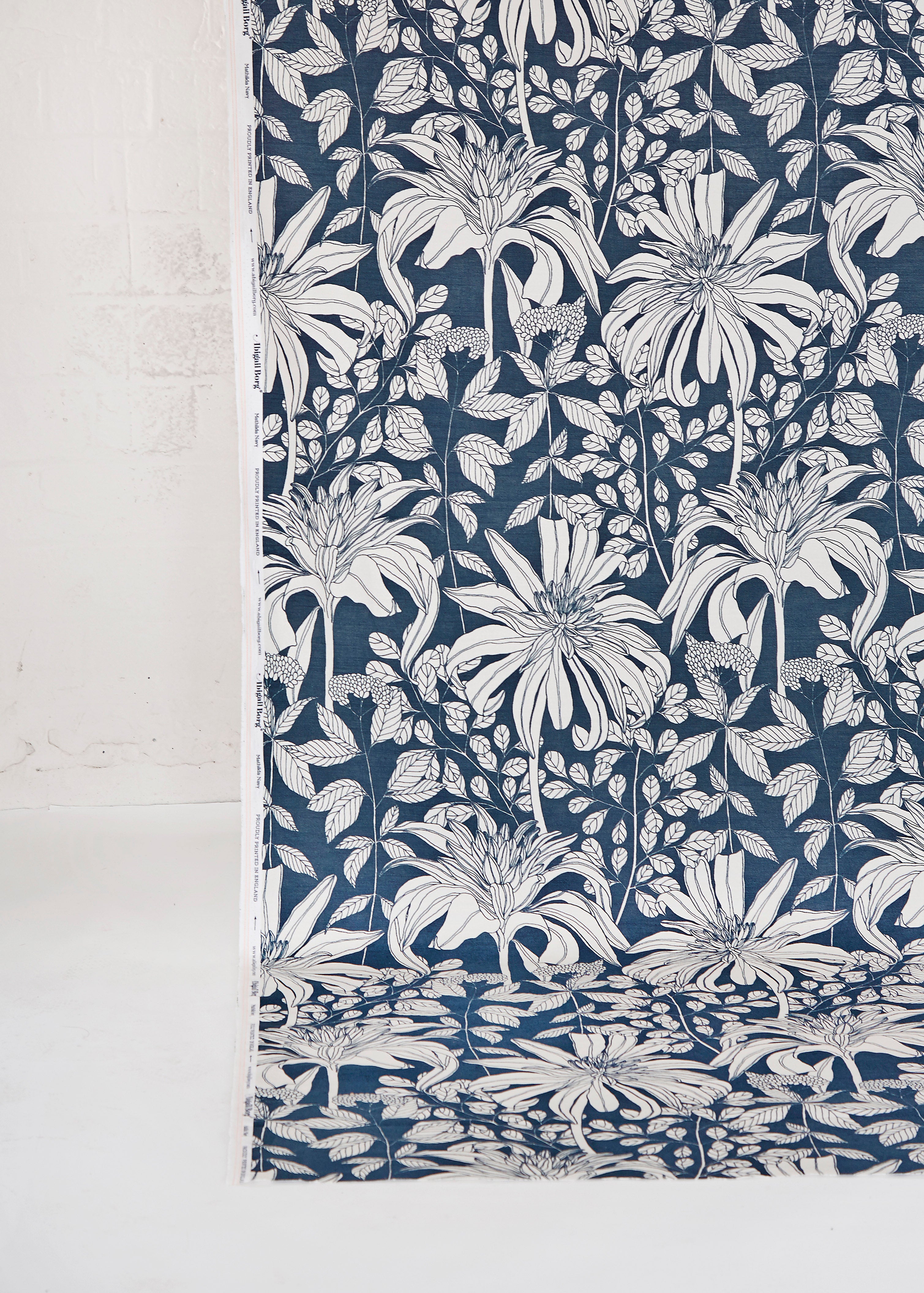 Draped fabric yardage in a floral print in black and white on a navy field.