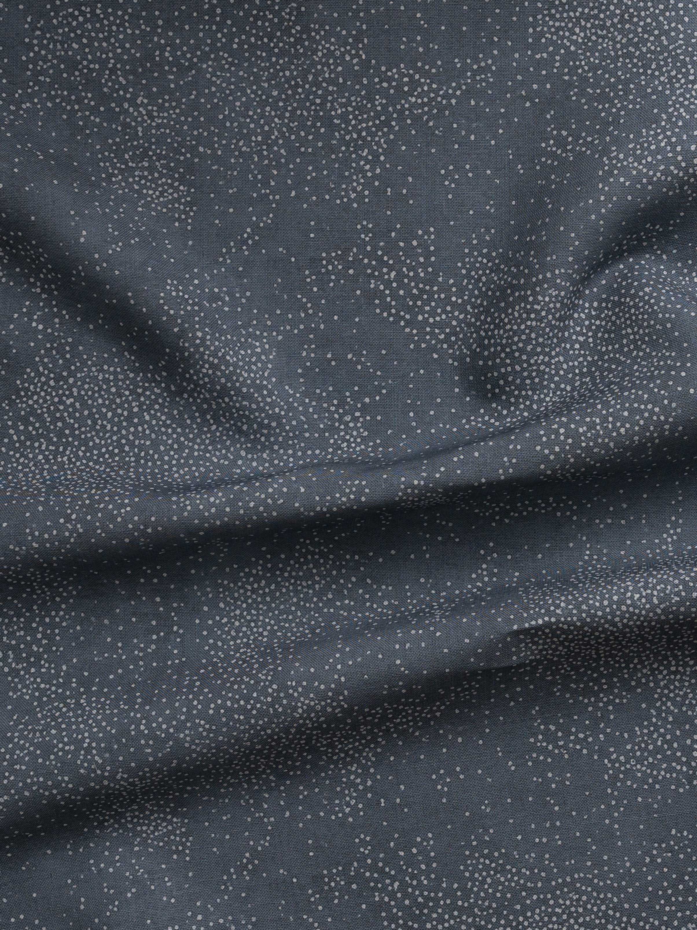 Detail of gently draped printed fabric with a white celestial dotted pattern on a cool blue background.