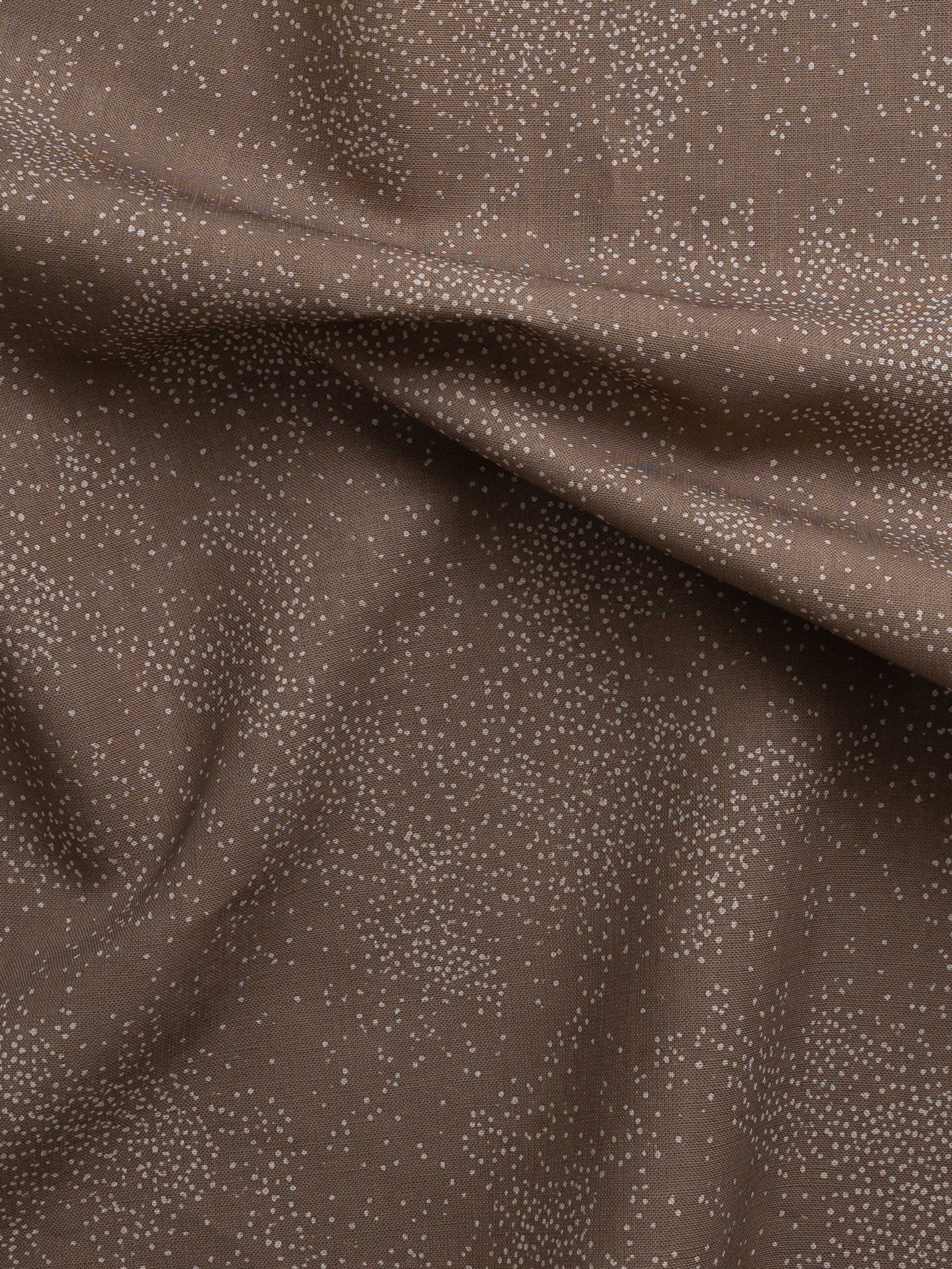 Detail of gently draped printed fabric with a white celestial dotted pattern on a warm clay background. 