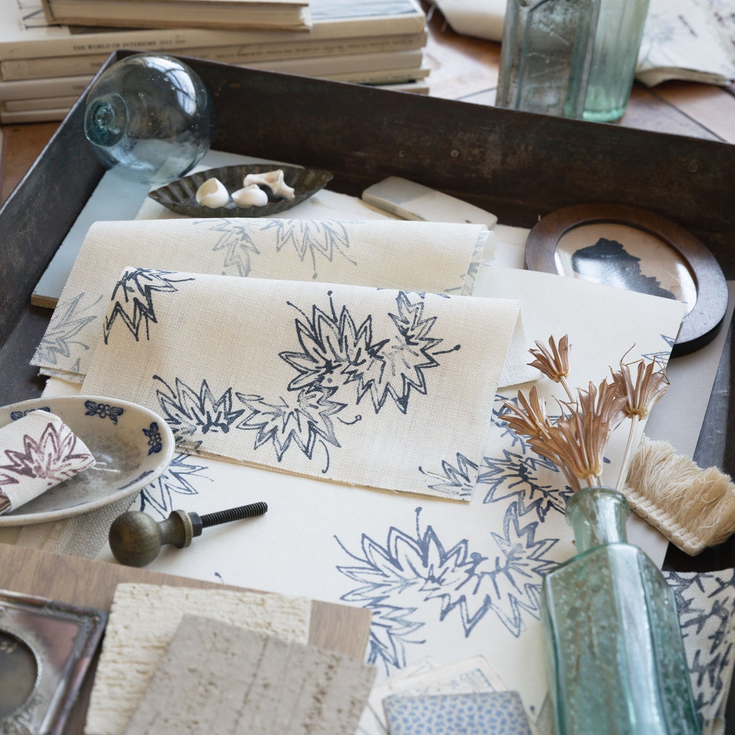 Desk setting with floral-patterned paper, inkwell, and bottles on a wooden surface.