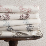 Stack of folded fabric with floral patterns on a wooden table against a textured wall.