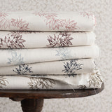 Stack of folded fabric with floral patterns on a wooden table against a textured wall.