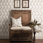 Wooden bench with floral cushion against a patterned wall with framed pictures.