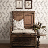 Wooden bench with floral cushion against a patterned wall with framed pictures.