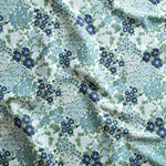 Close up of gently draped Indoor-Outdoor fabric with a dense flower and leaf pattern in shades of blue, green and white. 