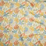Close up of gently draped Indoor-Outdoor fabric with a dense flower and leaf pattern in shades of  yellow, orange, blue, green and white. 