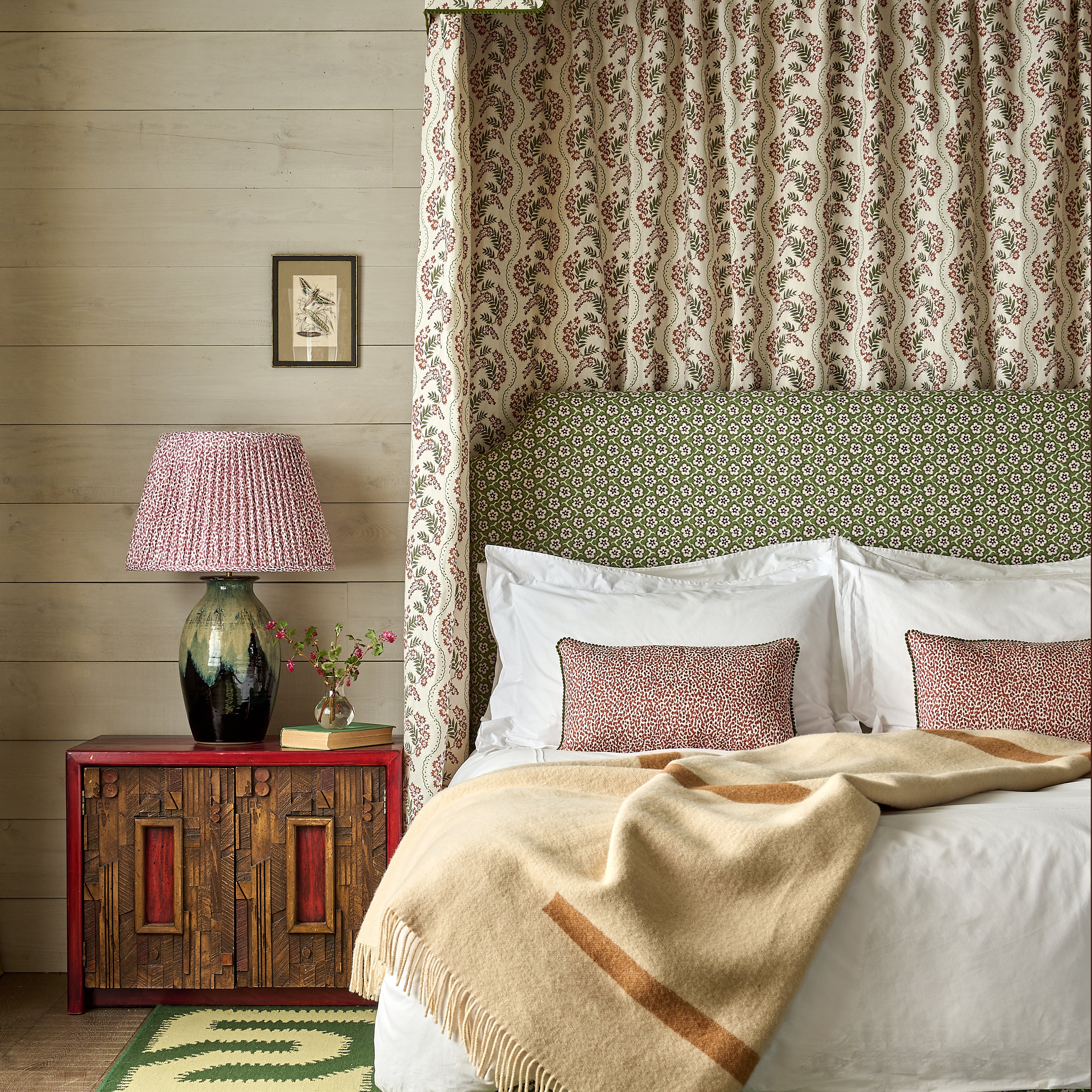 Bedroom with a canopy bed, patterned headboard, and wooden nightstand.