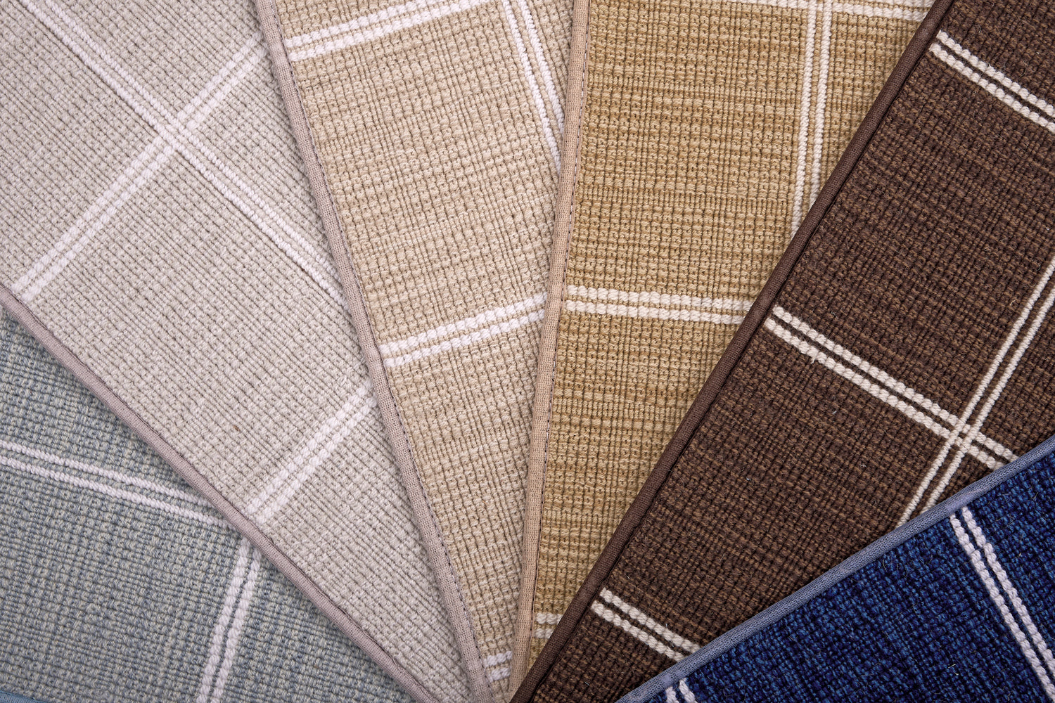 Broadloom carpet samples in plaid pattern in blue, tan, beige, brown and blue.
