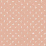 Detail of fabric in a repeating leaf print in cream on a light pink field.