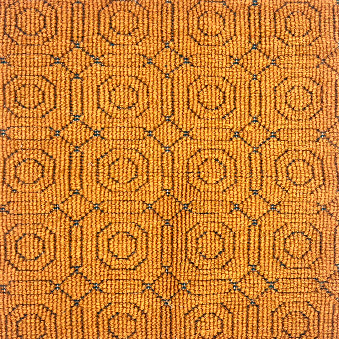 Handmade rug sample in a hexagonal linear motif in ochre with accents of navy. 
