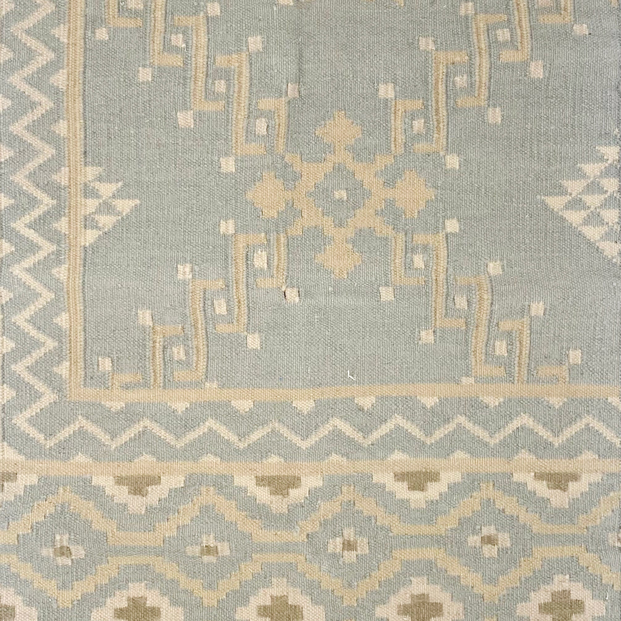 Patterned rug with geometric design on a light blue background
