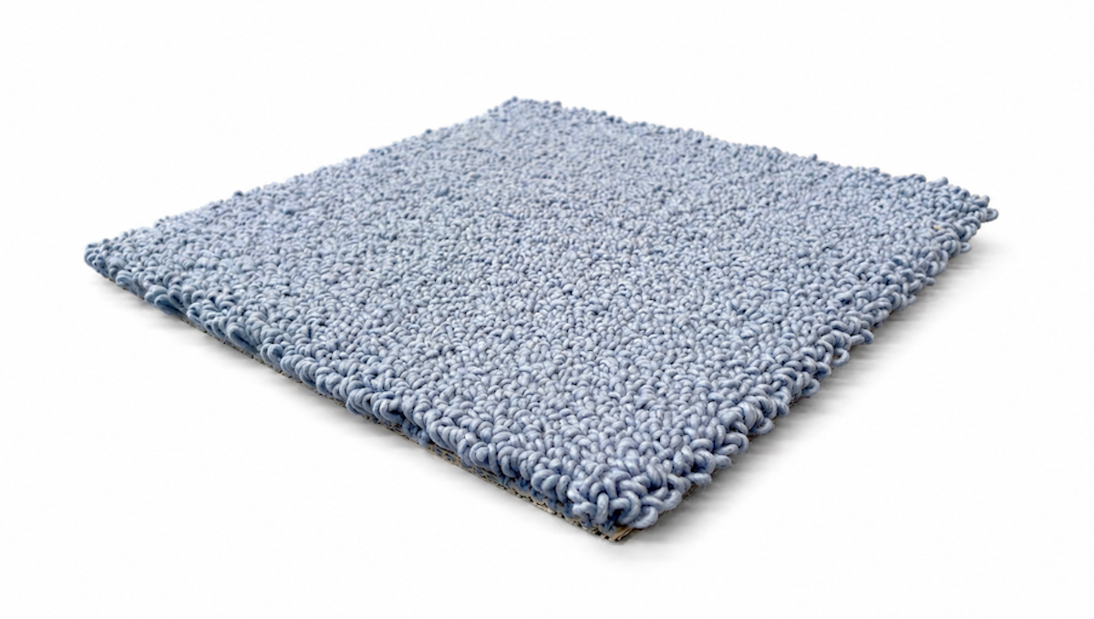 A square sample of light blue loop-pile carpet, shown at an angle on a clean white background.