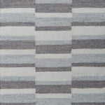 Flatweave rug in a broken stripe in shades of grey and cream.