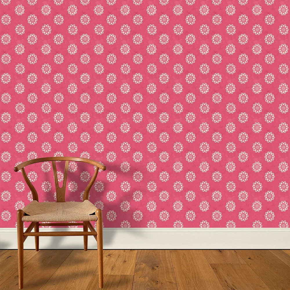A wooden chair stands in front of a wall papered in a playful repeating floral print in white on a magenta field.