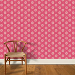 A wooden chair stands in front of a wall papered in a playful repeating floral print in white on a magenta field.