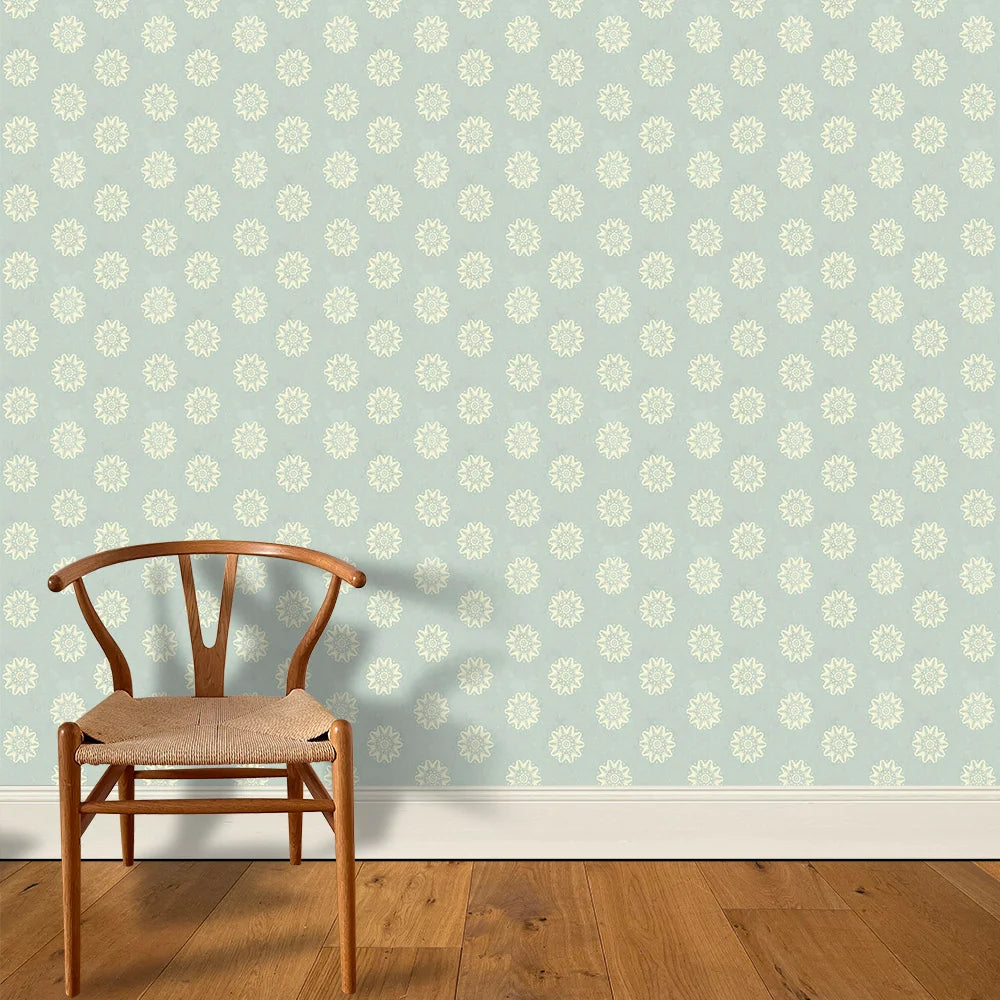 A wooden chair stands in front of a wall papered in a playful repeating floral print in cream on a light blue field.